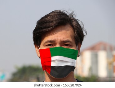 United Arab Emirates Flag On Hygienic Mask. Masked Asian Man Prevent Germs. Concept Of Tiny Particle Protection Or Virus Corona Or Covid 19.