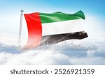 United Arab Emirates flag wavering in beautiful clouds with building skyline. The flag with drone shot in beautiful sky. UAE national flag for independence day.