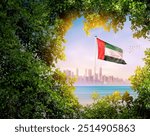 United Arab Emirates flag waving with modern skyline. A flag blow behind the tree leafs. UAE national flag for independence day.