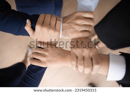 United business team holding wrists and making unbreakable hand square, community and support symbol. Group of engaged employees keeping teamwork, motivation, friendship spirit. Close up cropped shot