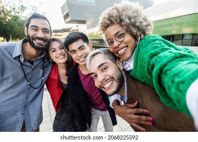 United group of happy multiracial young friends having fun outdoors - Diverse millennial people laughing together while taking selfie in city street - Teamwork, community and friendship concept