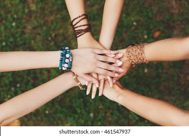 United Hands Of Young Females, Top View. Stylish Hands Of Girlfriends In Boho Hippie Bracelets At Green Grass Background. Togetherness And Support, Youth Fashion And Active Lesiure. Women Friendship