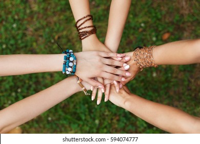 United Hands Of Young Females, Top View. Stylish Girlfriends In Boho Hippie Bracelets At Green Grass Background. Togetherness And Support, Youth Fashion And Active Lesiure. Women Friendship