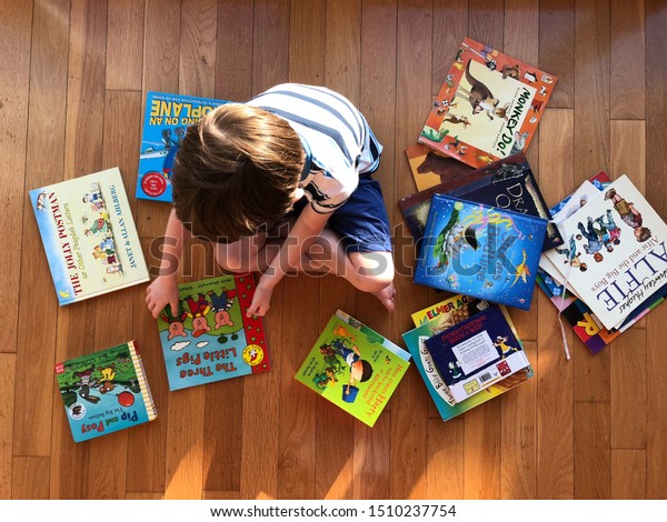 United Kingdom 9\
September 2019: little boy sitting on the floor surrounded by\
picture books and\
stories