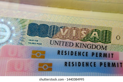 United Kingdom BRP (Biometrical Residence Permit) cards for Tier 2 work visa placed on top of UK VISA sticker in the passport. Close up photo. 