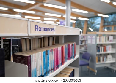 United Kingdom, Circa: November 2021: Shallow Focus Of The Work Romance Seen Atop A Book Shelf In A Library Setting. The Spacious Interior Is Visible In The Image.