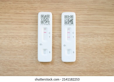 UNITED KINGDOM - March 26, 2022. Covid 19 Testing. Two LFT (Lateral Flow Test) Tests, Showing Positive And Negative Results. Flat Lay Of Covid-19 Tests On A Wooden Desk, UK