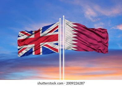 United Kingdom and Qatar two flags on flagpoles and blue cloudy sky
