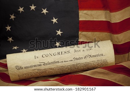 United States of America Declaration of Independence dated July 4, 1776 lying on an American flag. The flag, popularly attributed to Betsy Ross, was designed during the American Revolutionary War.