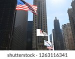 United States of America National Flag, State of Illinois Flag and Chicago City Flag all flying in the wind on the Michigan Avenue bridge under a sunny blue sky day