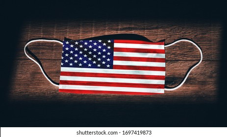 United States Of America National Flag At Medical, Surgical, Protection... Mask On Black Wooden Background. Coronavirus Covid–19, Prevent Infection, Illness Or Flu. State Of Emergency, Lockdown