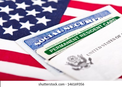 United States of America social security and green card with US flag on the background. Immigration concept. Closeup with shallow depth of field.