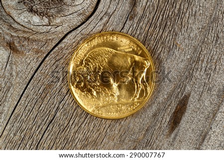 United States of American Mint Issued showing reverse side of American Buffalo coin, fine gold, on rustic wood. 