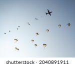 United States Army Soldiers and Paratroopers descending in the sky, from an Air Force C-130 military aircraft during an Airborne Operation.