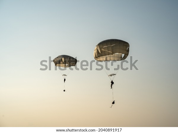 United States Army Soldiers and Paratroopers\
descending in the sky, from an Air Force C-130 military aircraft\
during an Airborne\
Operation.