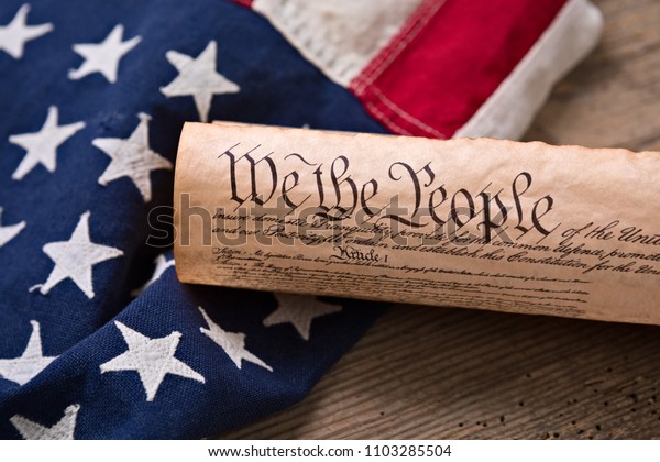 United States Constitution,\
rolled in a scroll on a vintage American flag and rustic wooden\
board