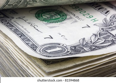 United States one dollar bill laying in a stack of money.