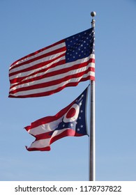 United States patriotic flag and Ohio State flag waving against blue sky      