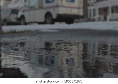 United States Postal Service Truck Seen In The Reflection Of Freshly Melted Ice  