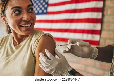 United States Servicewoman Getting Inoculated During The Coronavirus Pandemic. Happy Female Soldier Smiling Cheerfully While Receiving The Covid-19 Vaccine In The Army Hospital.