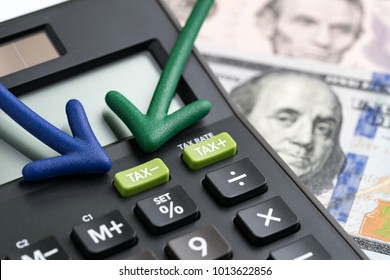 United States tax cuts, reform / reduce concept, arrows pointing to TAX minus button on calculator with background of blurred US Dollar banknotes, government offer tax deduction policy.