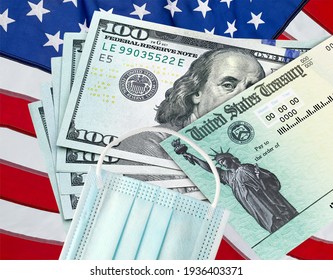 United States Treasury check with US currency, American flag and surgical or medical covid mask. Coronavirus economic impact stimulus payments or IRS tax refund. 