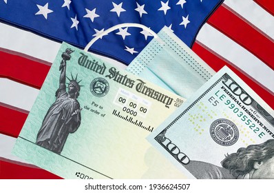 United States Treasury Check With US Currency, American Flag And Surgical Or Medical Covid Mask. Coronavirus Economic Impact Stimulus Payments Or IRS Tax Refund. 