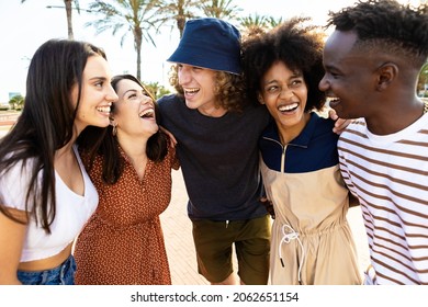 United young adult friends laughing together - Multiracial happy people having fun outdoors - Smiling hipster students hugging each other while celebrating - Youth, community and unity concept - Powered by Shutterstock