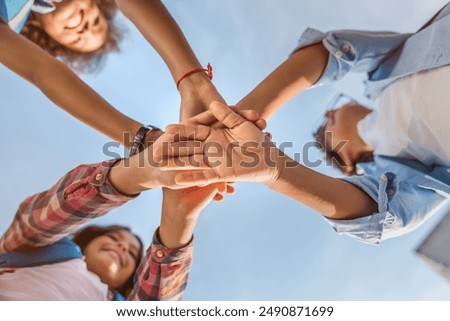 Unity concept. Bottom view of diverse multiethnic elementary middle school kids children pupils classmates friends boys and girls putting their hands together indoors on the background of the sky