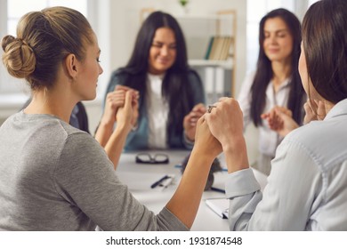 Unity Concept. Team Of Happy Young Business Women Holding Hands With Eyes Closed Sitting Together Around Office Table In Corporate Group Meeting. Value, Respect, Support And Believe In Your Colleagues