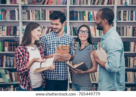 Unity and connection of people. Four multi ethnic students friends, discussing the books they read, wearing casual clothes, enjoying, smiling, laughing, gesturing