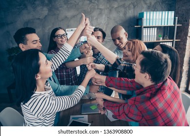 Unity of positive managers colleagues cooperating showing strength growth gesture place fists together in comfortable board room in checkered outfit casual shirts glasses