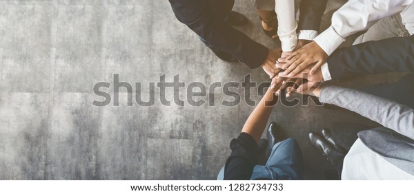 Unity and teamwork. Business people\
putting their hands together, top view, copy\
space