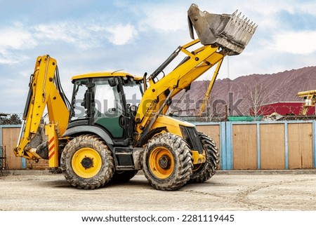 The universal backhoe loader lifted up the bucket on the construction site. Rental of construction equipment for earthworks. Universal construction equipment. Excavation