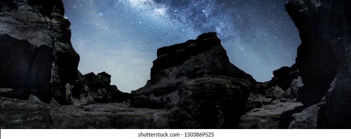 Universe space shot of nebula and milky way on hill under amazing starry blue night sky, large ravine. Silhouette of Snow Mountain Grand Canyon of U Thong Stone Mill Suphanburi, Stonehenge of Thailand - Powered by Shutterstock