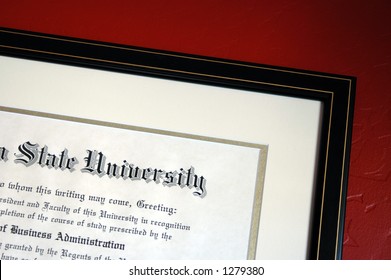 University Degree Framed And Hanging On Textured Red Wall.