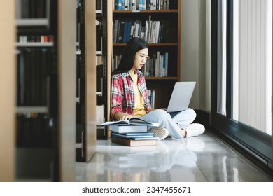 University Library: Beautiful smart asian university student uses Laptop, Writes Notes for Paper, Essay, Study for class assignment. Focused students learning, studying for college exams. - Powered by Shutterstock