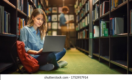 University Library: Gifted Beautiful Caucasian Girl Sitting On Floor, Uses Laptop, Writes Notes for Paper, Essay, Study for Class Assignment. Diverse Group of Students Learning, Studying for Exams. - Powered by Shutterstock