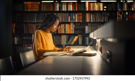 University Library: Gifted Black Girl uses Laptop, Writes Notes for the Paper, Essay, Study for Class Assignment. Students Learning, Studying for Exams College. Side View Portrait with Bookshelves - Shutterstock ID 1752957992