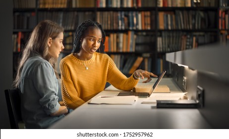 University Library: Two Gifted Girl Students Study, Use Laptop Computer, Help Each Other with Advice, Working on Assignment and Preparing for Exams. Focused Smart Student Learning, Studying for Exams