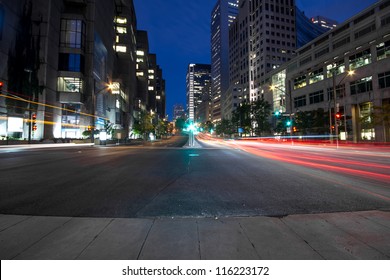 University Street in Montreal with silhouette cars with red rear light and traffic light, early in the morning with office building in background to dusk.