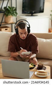 University Student Eating Breakfast When Attending Online Class And Writing Down Important Details