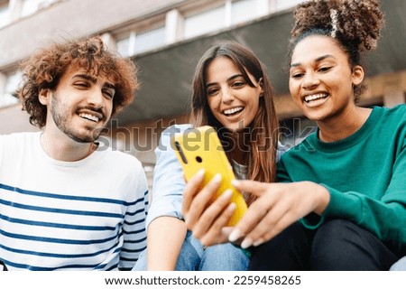 University student friends using mobile phone together to share content on social media