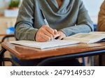 University student, hand and writing in classroom with books for english literature or language for exam. Person, college and scholarship for learning or education, knowledge and study academic work.