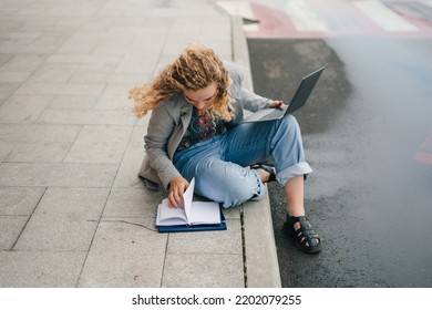 University Student Learning Online Using Laptop Computer, Taking Notes, Sitting Outside Uni Campus Area. Preparing For Exam Outside. Learning Language