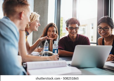 University students sitting together at table with books and laptop. Happy young people doing group study in library. - Shutterstock ID 508251865