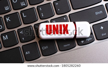 UNIX - the word on a white flash drive, lying on a black laptop keyboard. Computers concept