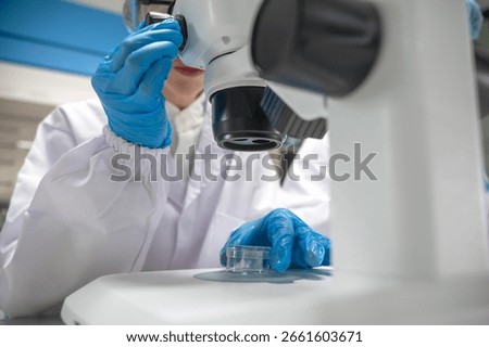Unknown biologist working with microscope slide in bio laboratory