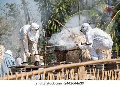 Unknown blacksmith holding a hot crucible by the iron pliers from furnace before pouring the melting gold into the statue block. The process to making of metal statue in local Thailand traditional. - Powered by Shutterstock