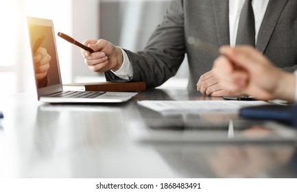 Unknown businessmen and woman sitting, using laptop computer and discussing questions at meeting in sunny office, close-up. Success concept - Shutterstock ID 1868483491